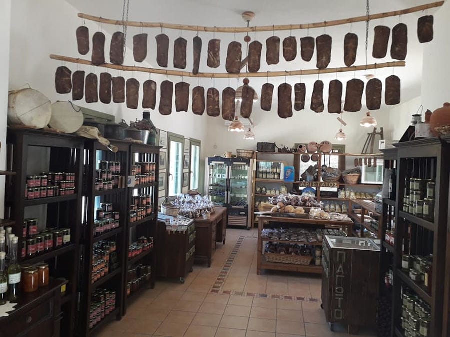 wooden shelves and tables with glass jars and cured meat hanging from the ceiling inside Aristaios' store